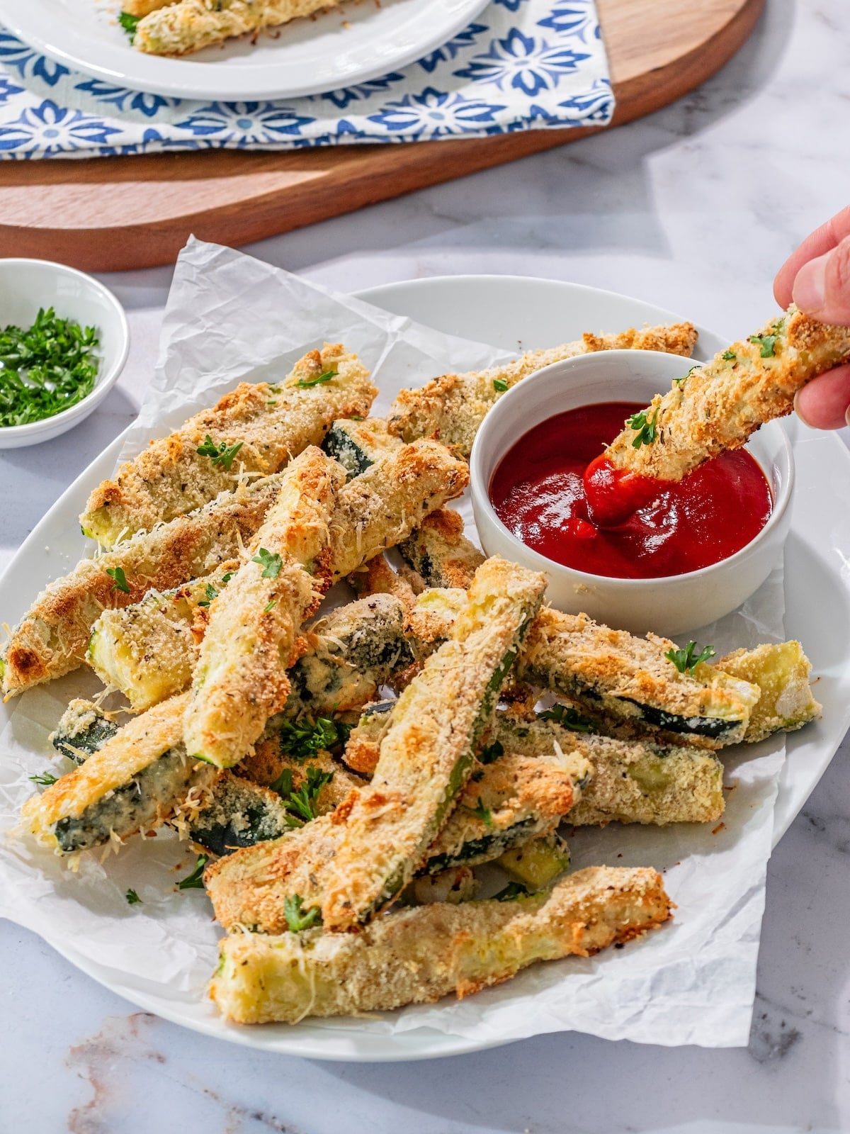 A baked zucchini stick being dipped into sauce.