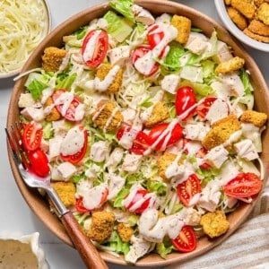 Healthy caesar salad with dressing on top and a fork on the side.