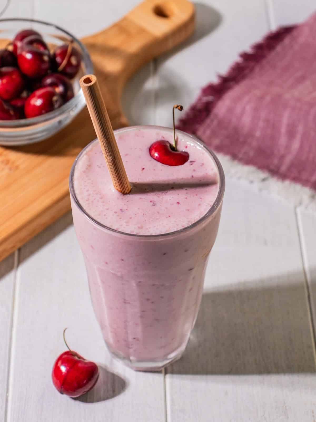 A glass filled with cherry smoothie on a table.