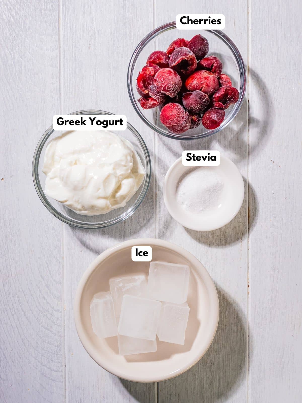 Ingredients to make this cherry smoothie in bowls on a table.