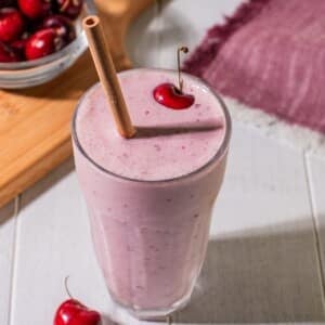 Healthy cherry smoothie in a tall glass with a straw.