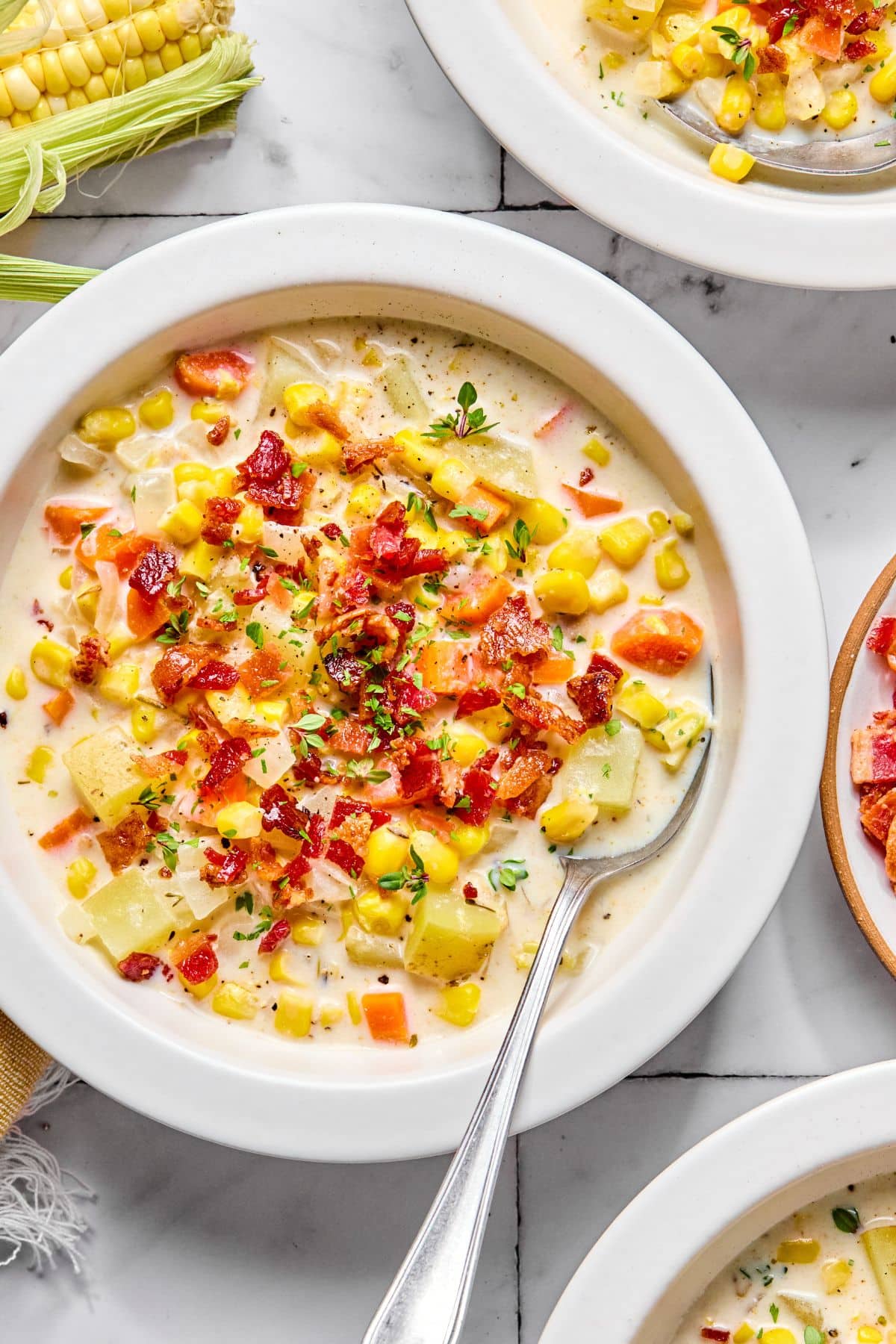 A bowl with corn chowder with a spoon on the side.