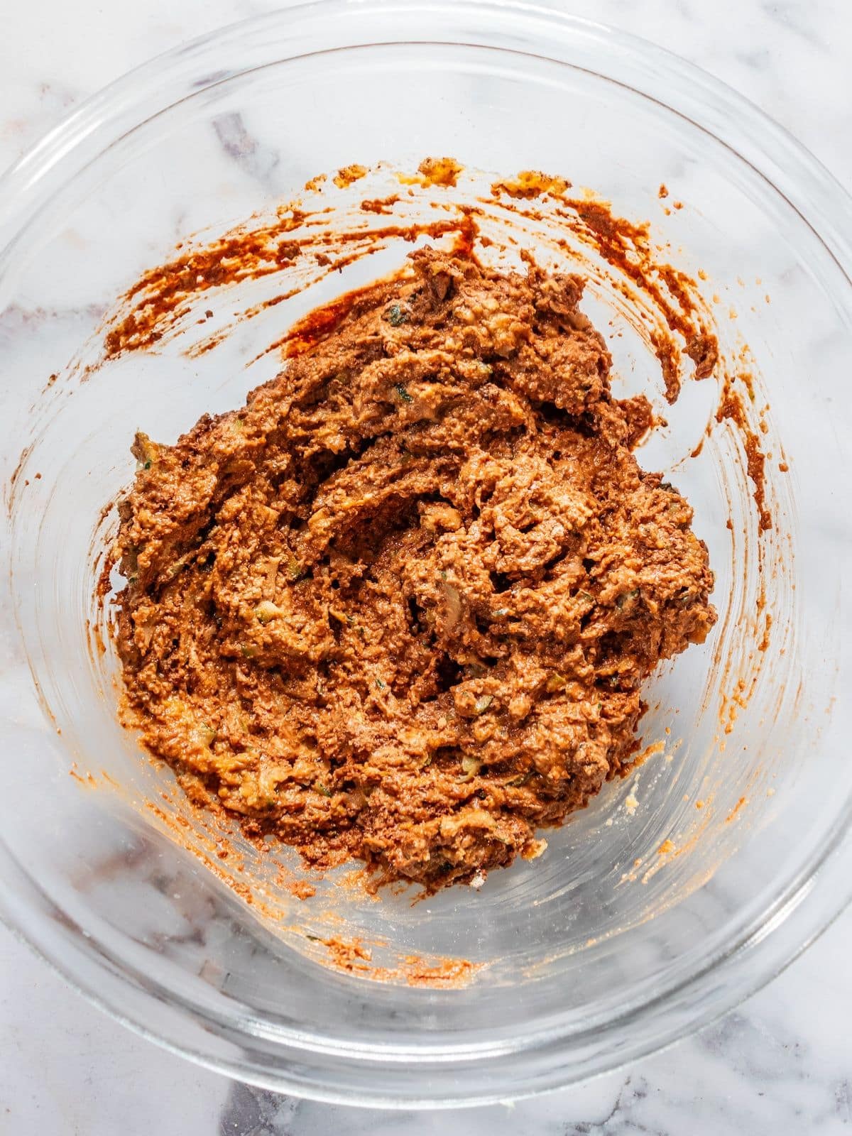 Zucchini, cocoa powder, ground oats, baking soda, espresso powder and salt mixed in a bowl.