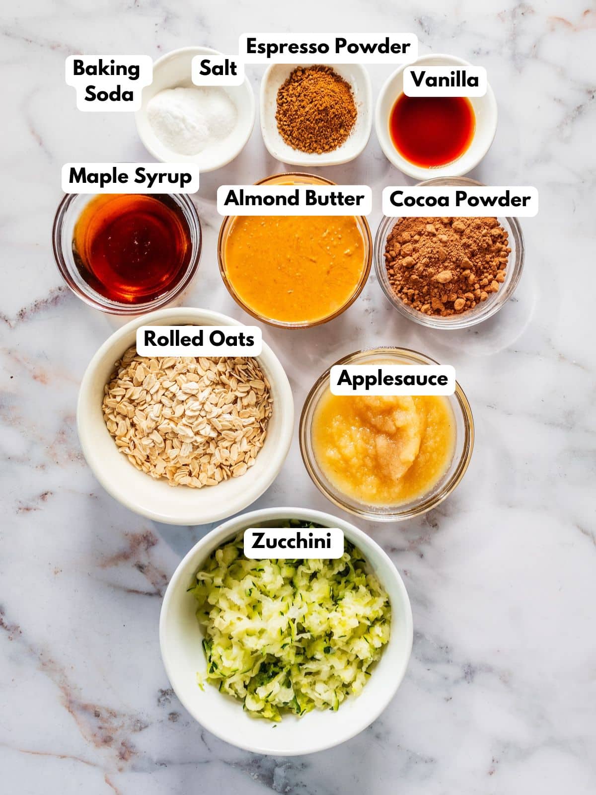 Ingredients to make these zucchini brownies on bowls on a table.