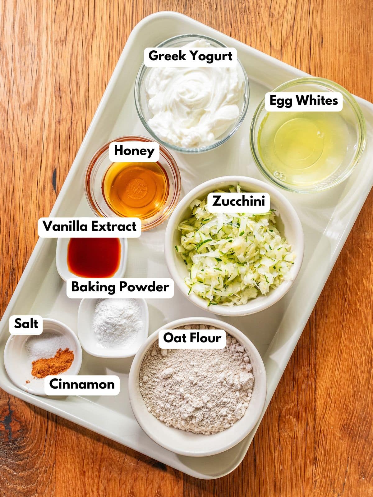 Ingredients to make these zucchini pancakes in bowls on a table.