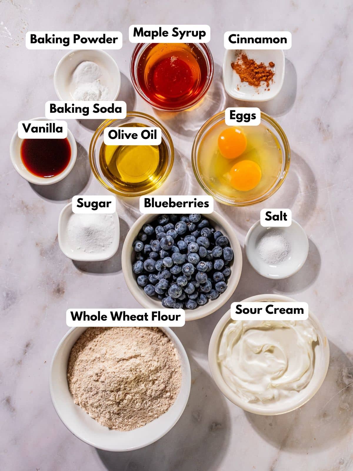 Ingredients to make these sour cream blueberry muffins in bowls on a table.