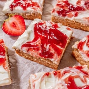 Strawberry cheesecake bars layed out on parchment paper.