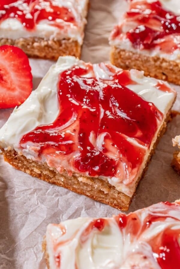 Strawberry cheesecake bars layed out on parchment paper.