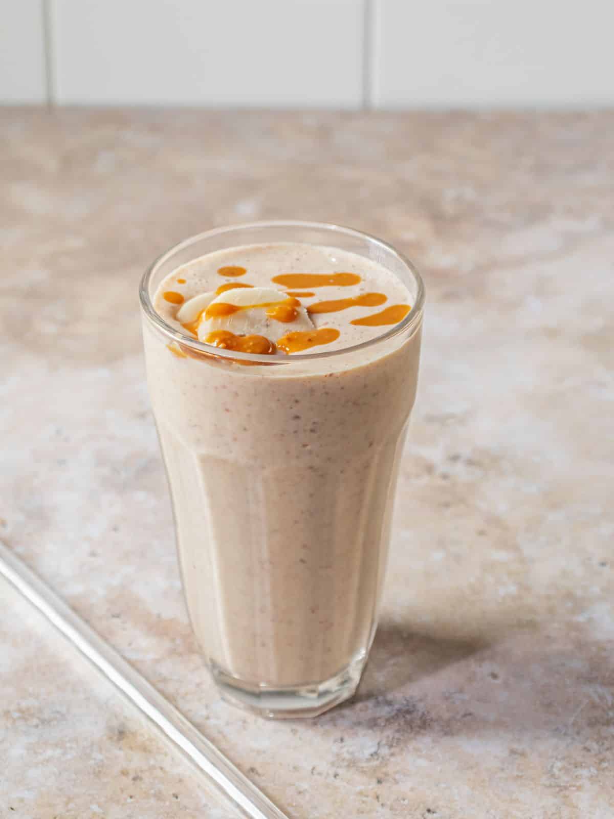 The completed smoothie poured into a glass and topped with banana and peanut butter.