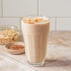 A glass filled with banana yogurt smoothie on a table.