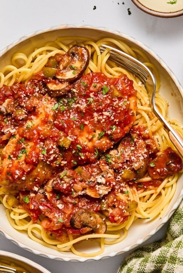 Crockpot chicken cacciatore served in a bowl over pasta.