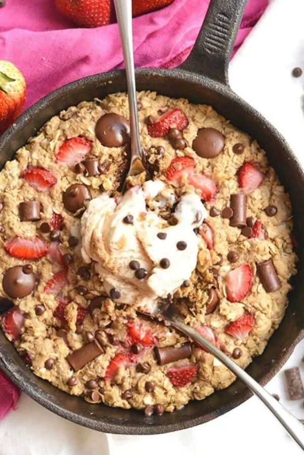 Gluten free skillet cookie with spoons scooping out some.