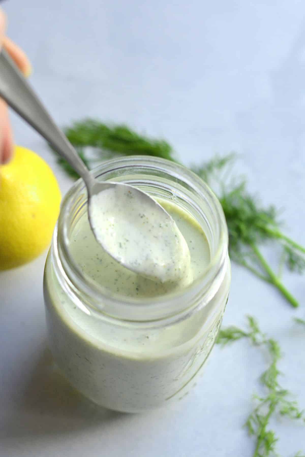 A spoon scooping out some low calorie ranch dressing.
