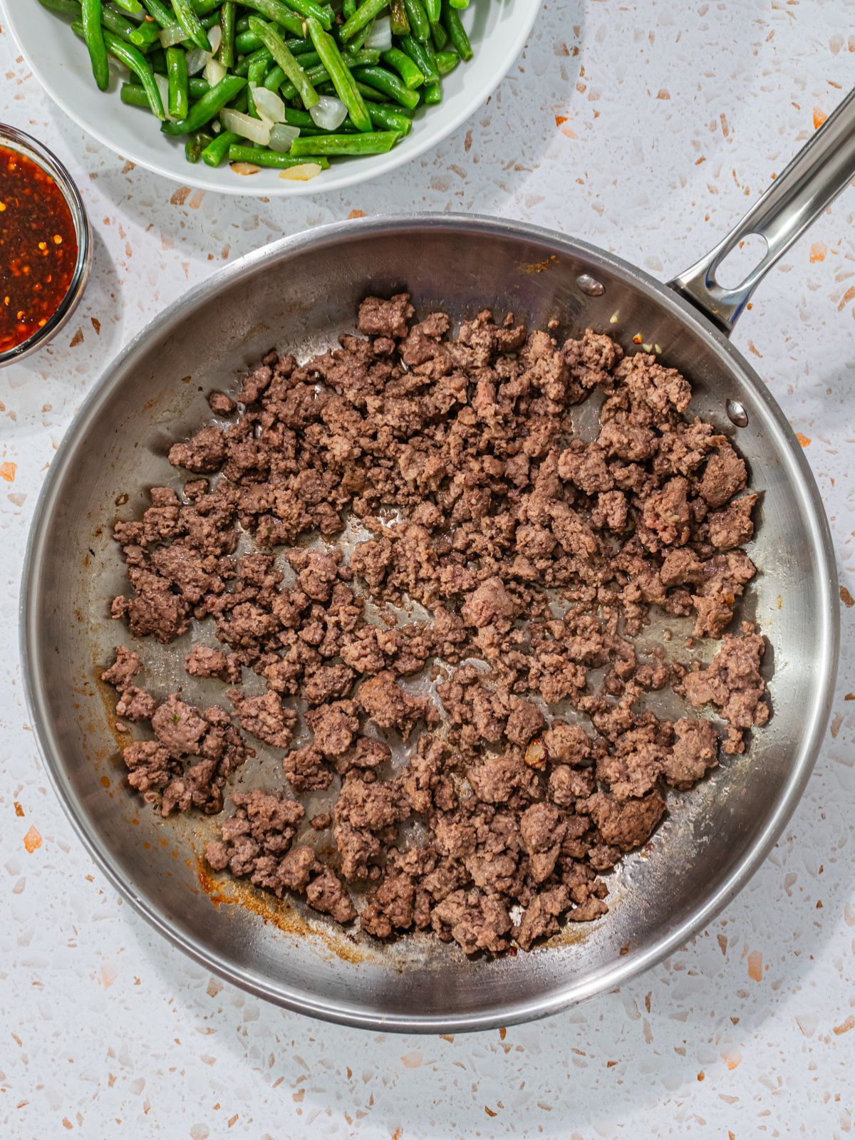 Ground beef cooked in pan.