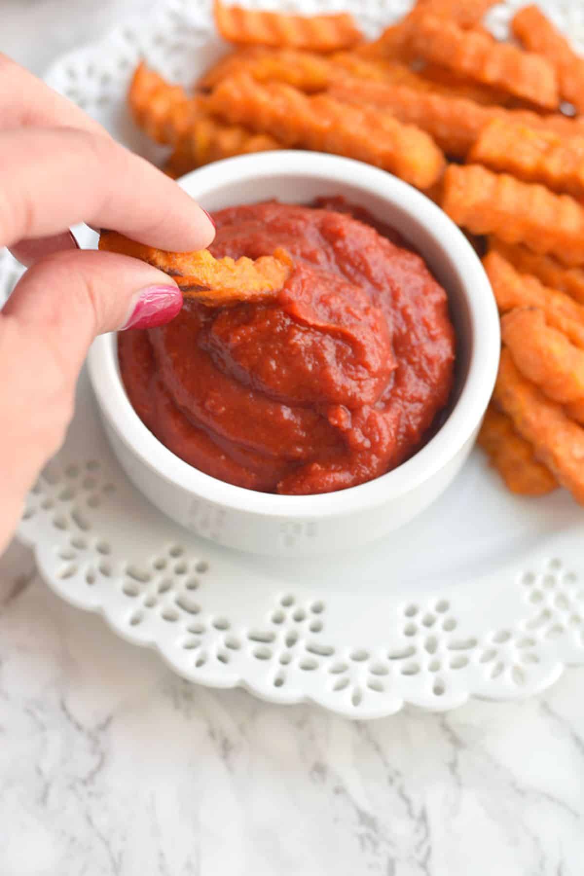 A french fry being dipped into the ketchup.