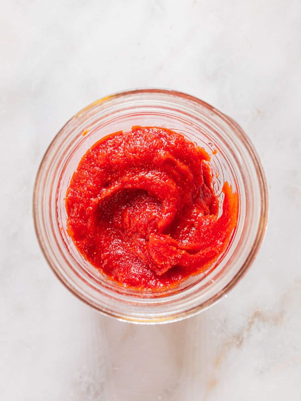 The completed ketchup added to a mason jar.