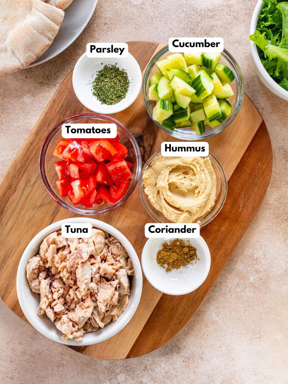Ingredients to make this hummus and tuna salad in bowls on a cutting board.