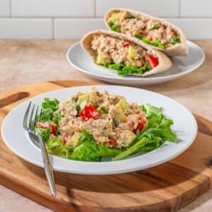 Hummus tuna salad on a plate with a sandwich in the back.
