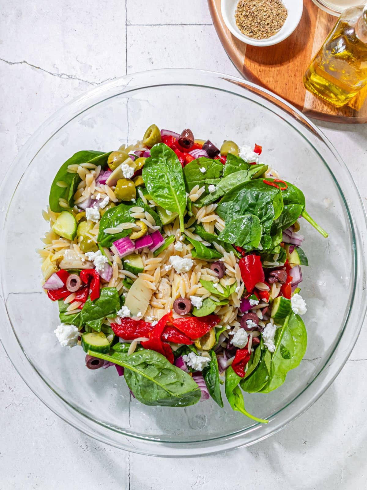 All the Greek orzo pasta salad ingredients in a bowl.