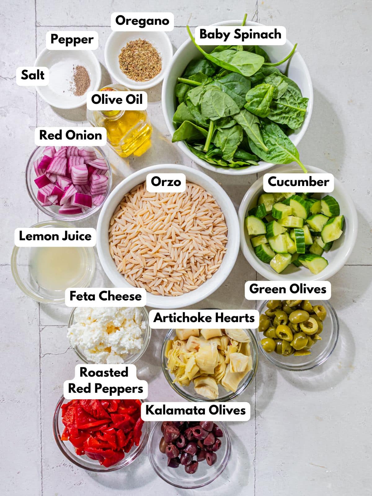 Ingredient to make this orzo pasta salad in bowls on a table.