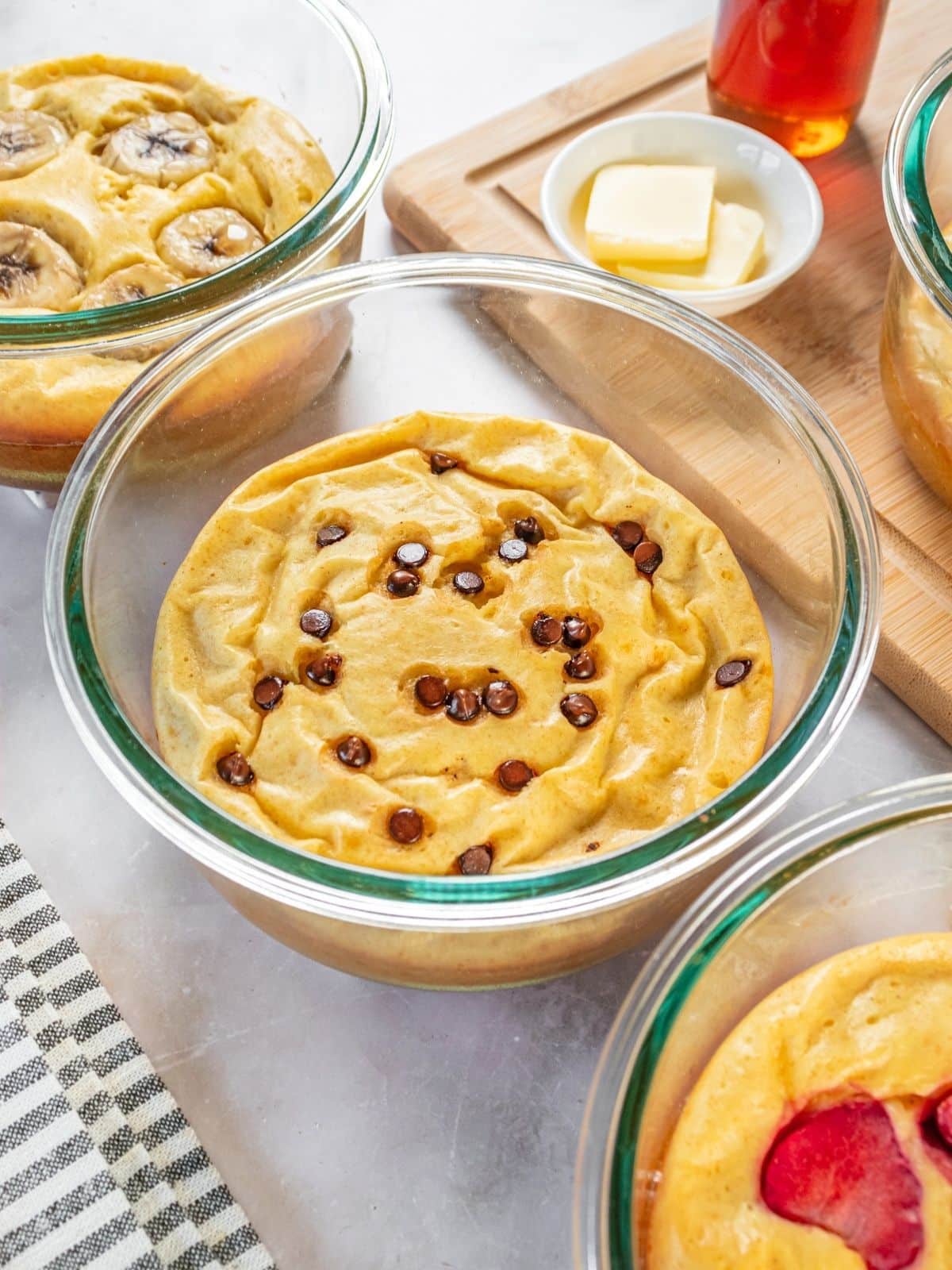 Pancake bowls with various toppings such as chocolate chips, bananas, and strawberries.