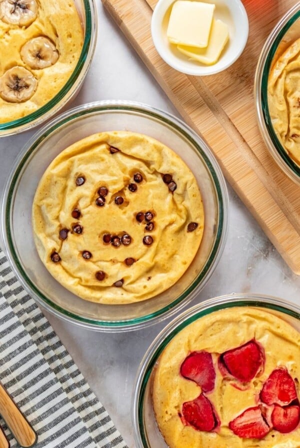 Four protein pancake bowls on a table each topped with a different topping.