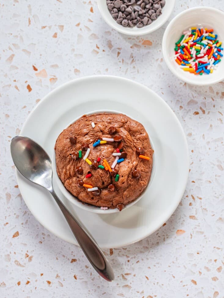 A protein cookie in a bowl with a spoon on top.