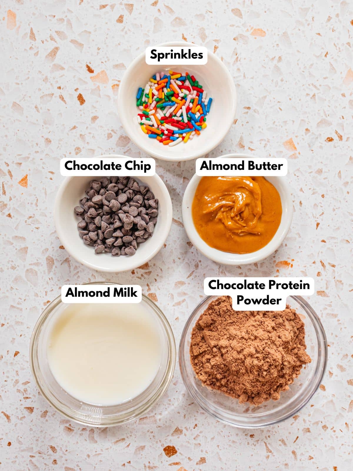 Ingredients to make these protein cookies in bowls on a table.