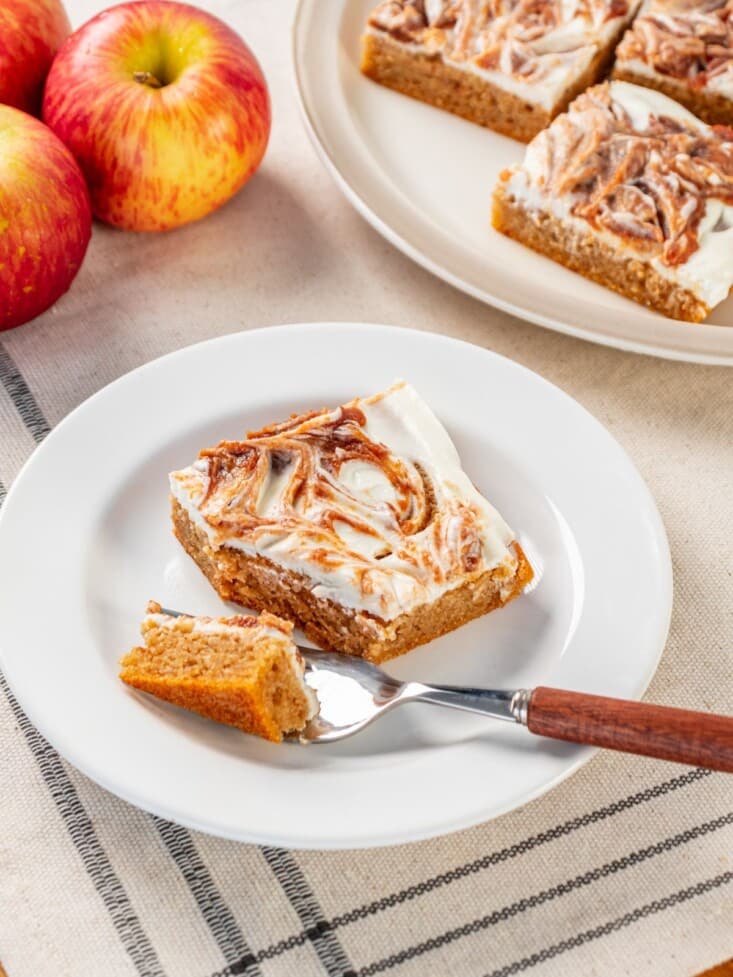 A apple cheesecake square with a fork taking a piece out.