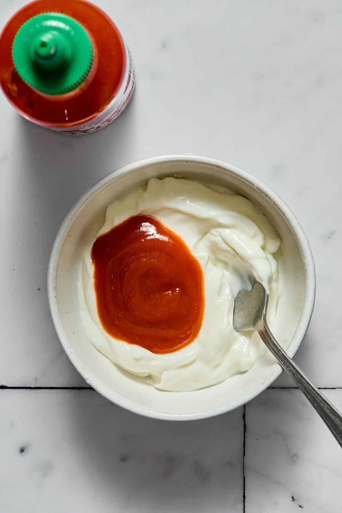 Greek yogurt with sriracha sauce together in a small bowl.