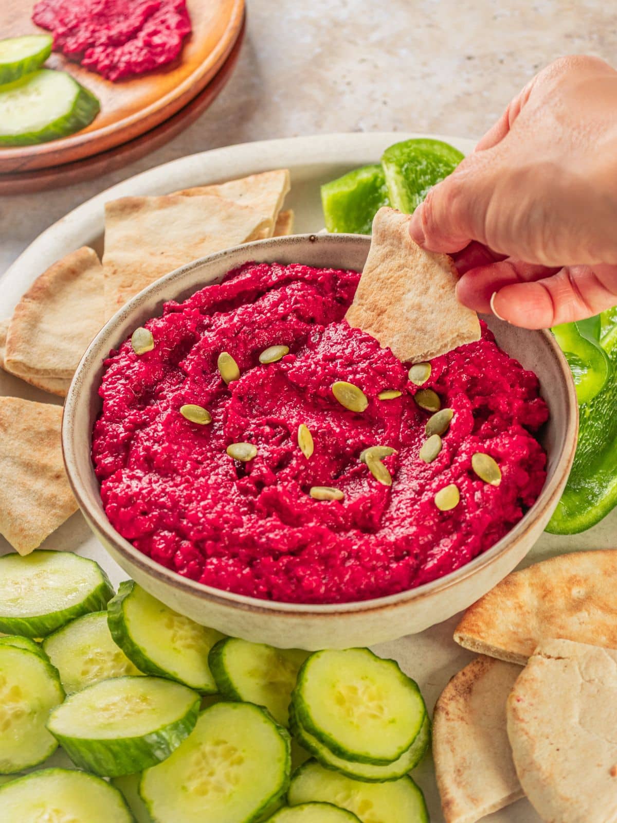 A chip scooping some beet hummus.