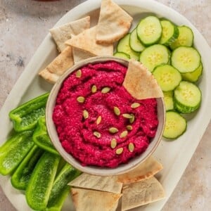 A platter with beet hummus in the center.