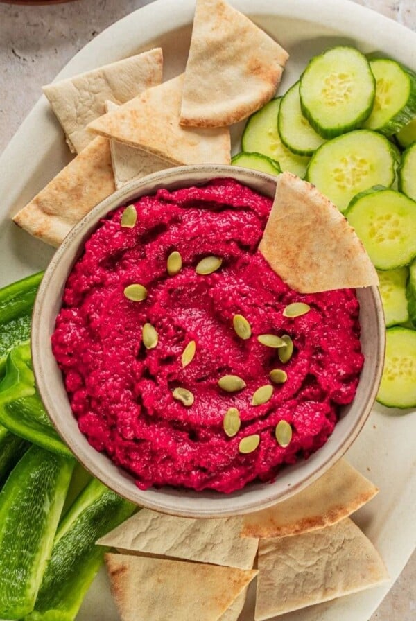 A platter with beet hummus in the center.