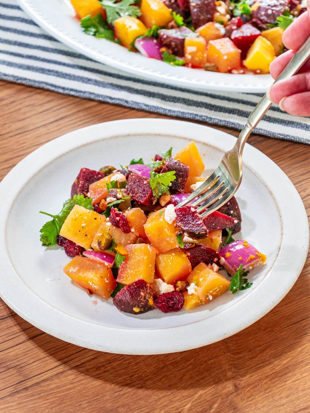 A fork taking some beet salad from a plate.