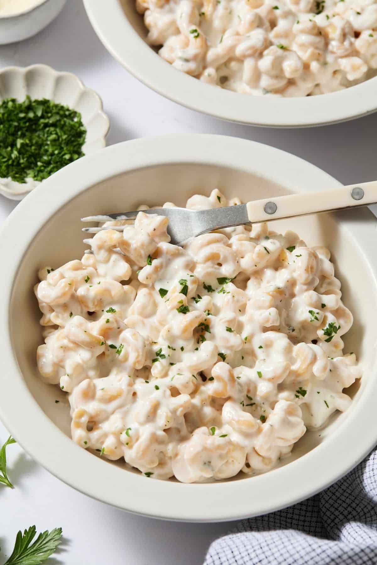 Pasta alfredo in a bowl with a fork on top.