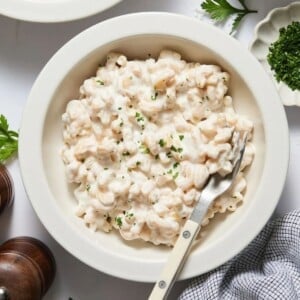 Cottage cheese alfredo sauce mixed into pasta in a bowl with a fork resting on the side.