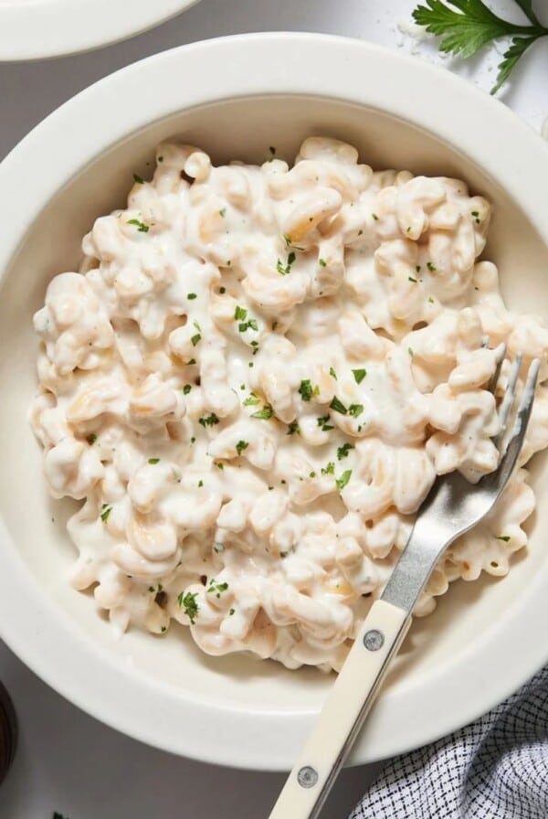 Cottage cheese alfredo sauce mixed into pasta in a bowl with a fork resting on the side.