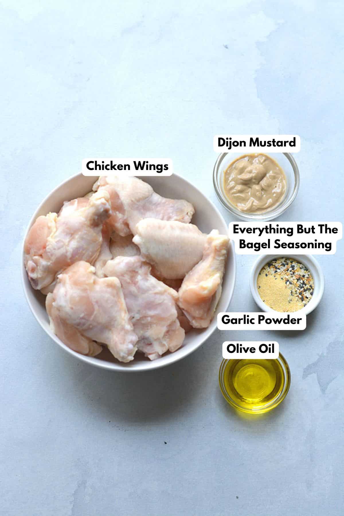 Ingredients to make these air fryer wings in bowls on a table.