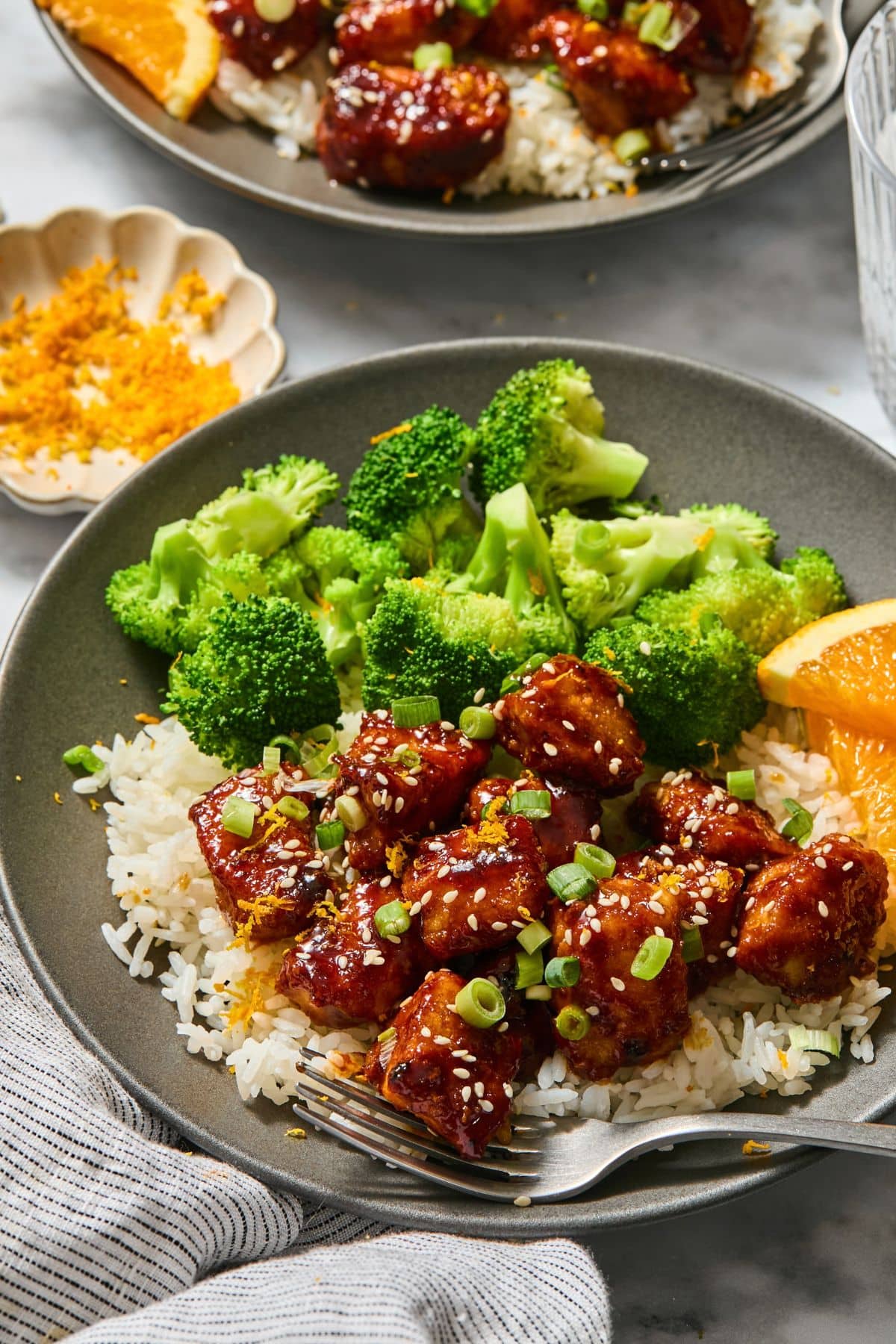 A plate of orange chicken with a side of broccoli.
