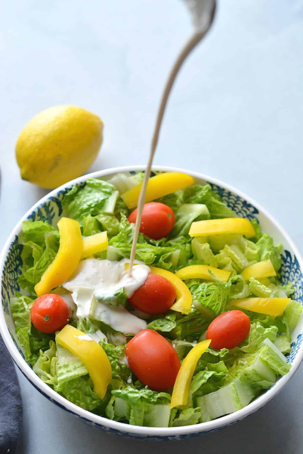 Healthy Caesar dressing being poured on a salad.