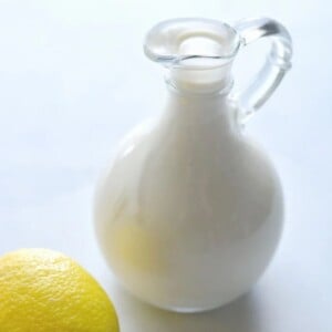 A mini glass pitcher with low calorie caesar dressing inside it.