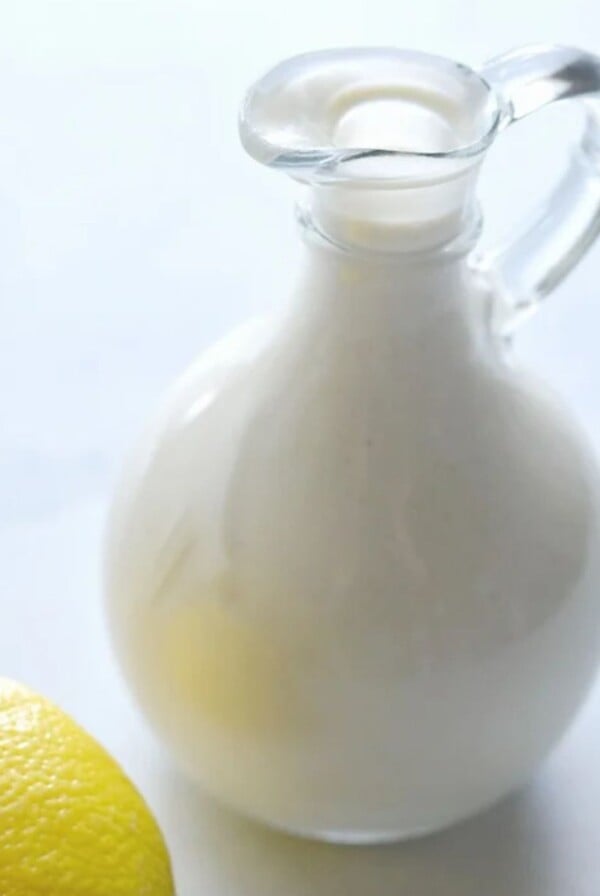 A mini glass pitcher with low calorie caesar dressing inside it.