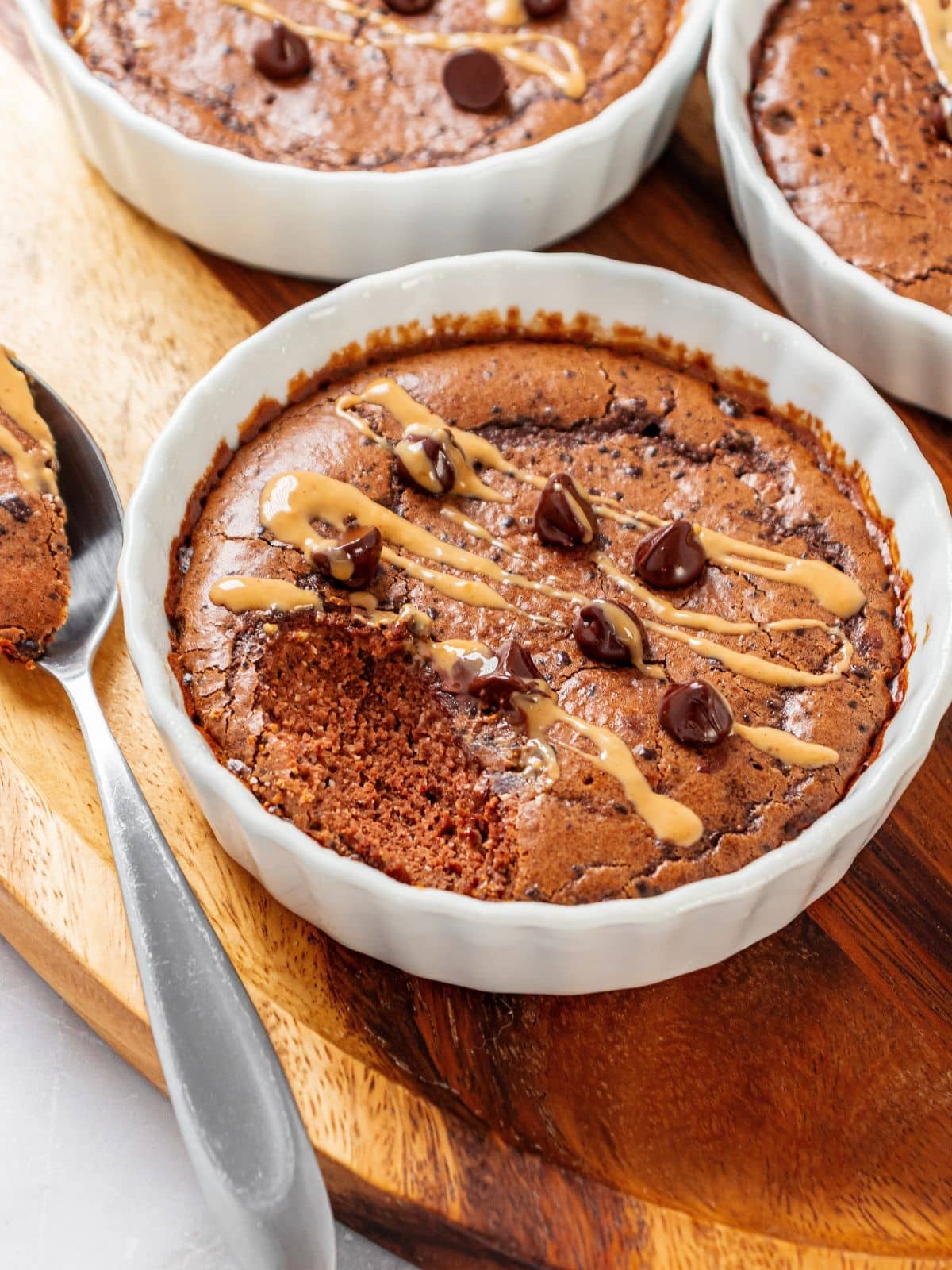 A spoon on the side of the mug cake with chocolate chips on top and a bite missing.