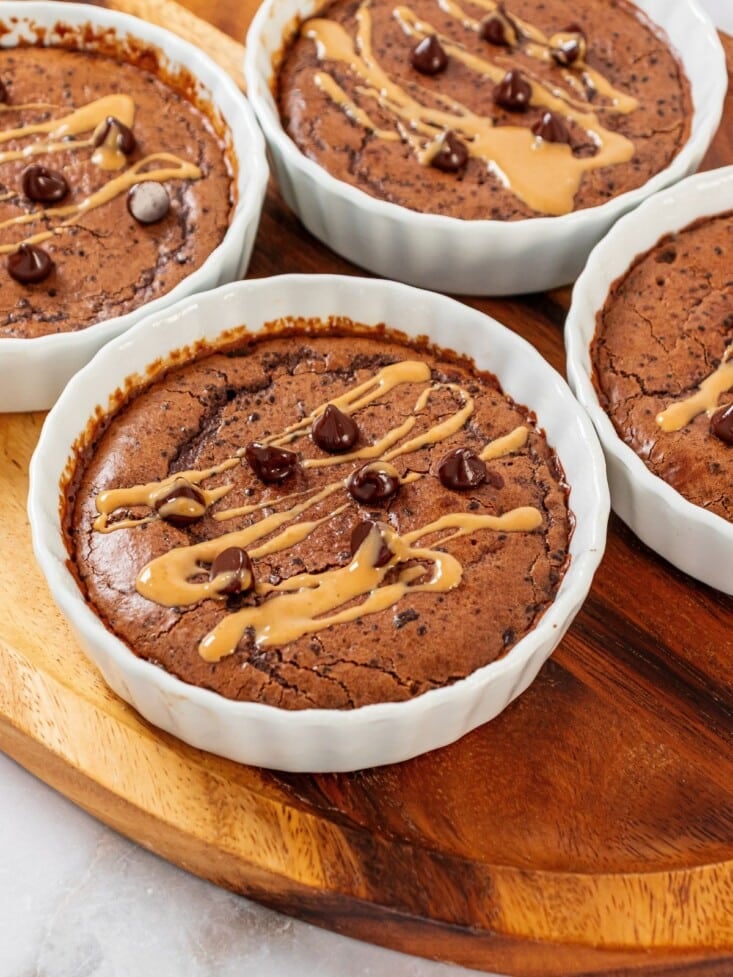 Four protein mug cakes in ramekins on a cutting board.