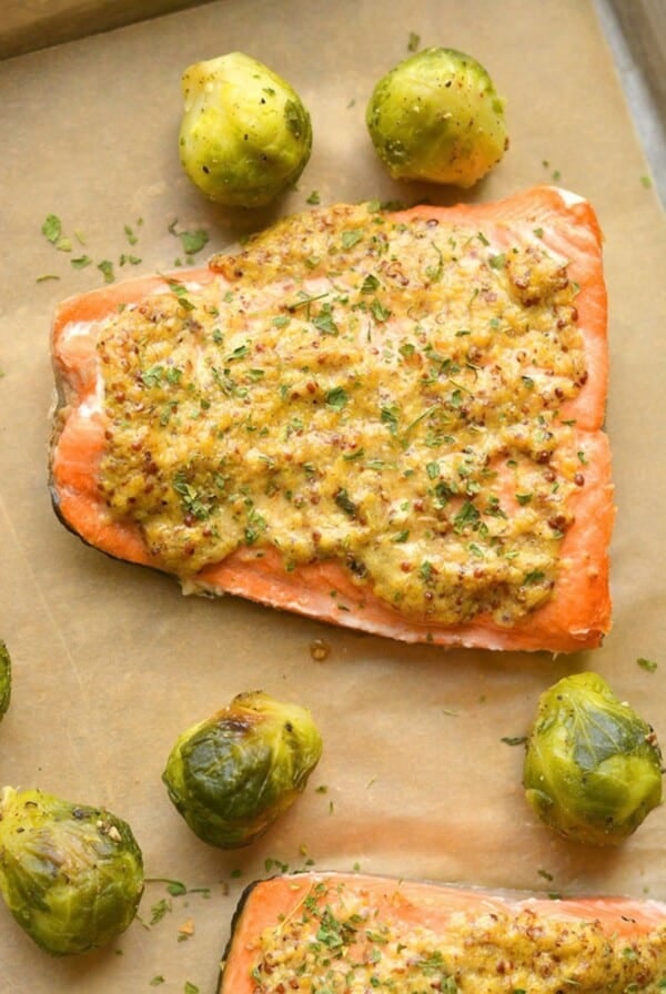 Air fryer salmon on parchment paper with brussels sprouts.