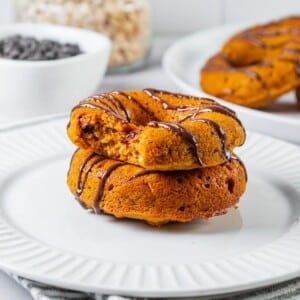 Baked pumpkin donuts stacked with a bite taken out of the top donut.