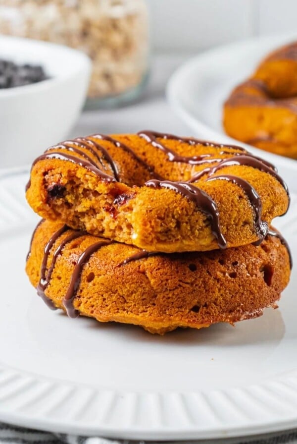 Baked pumpkin donuts stacked with a bite taken out of the top donut.