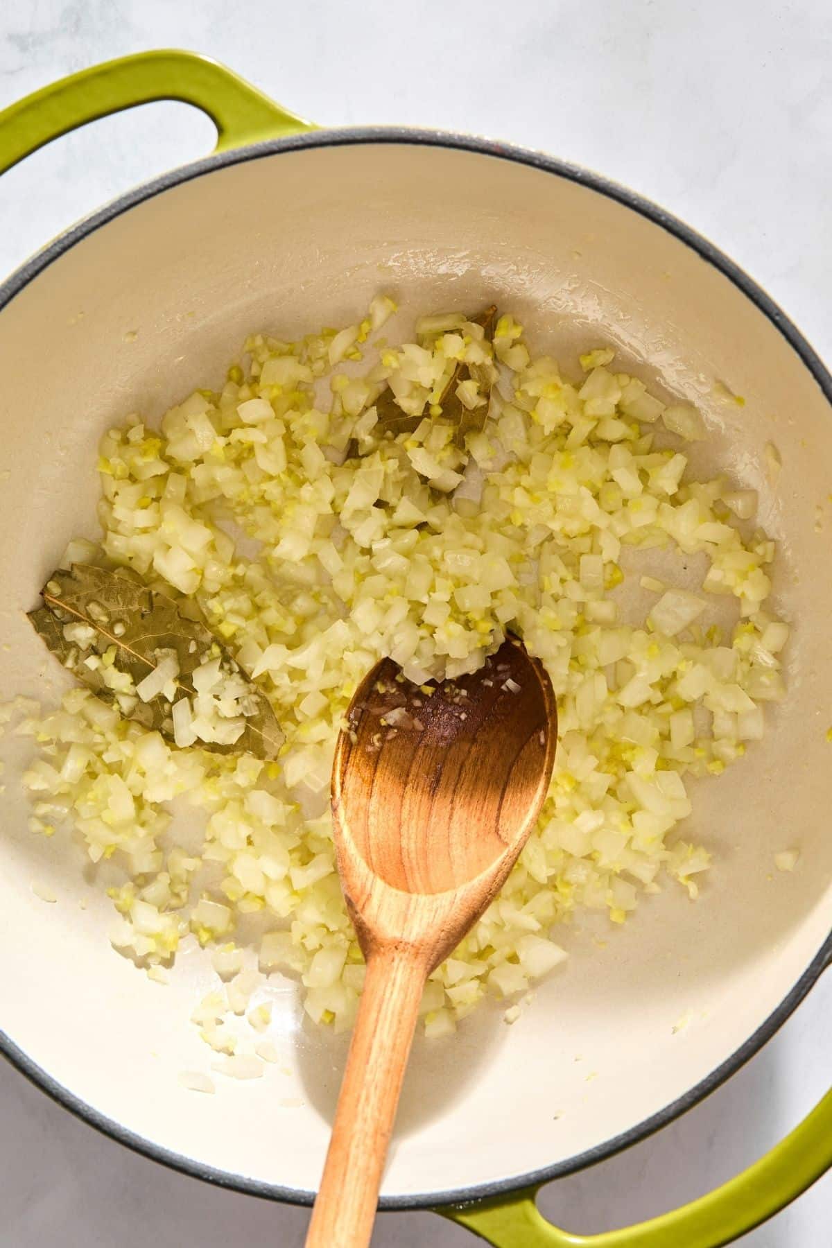 Minced garlic, onion, bay leaves and ginger cooking in a pot.