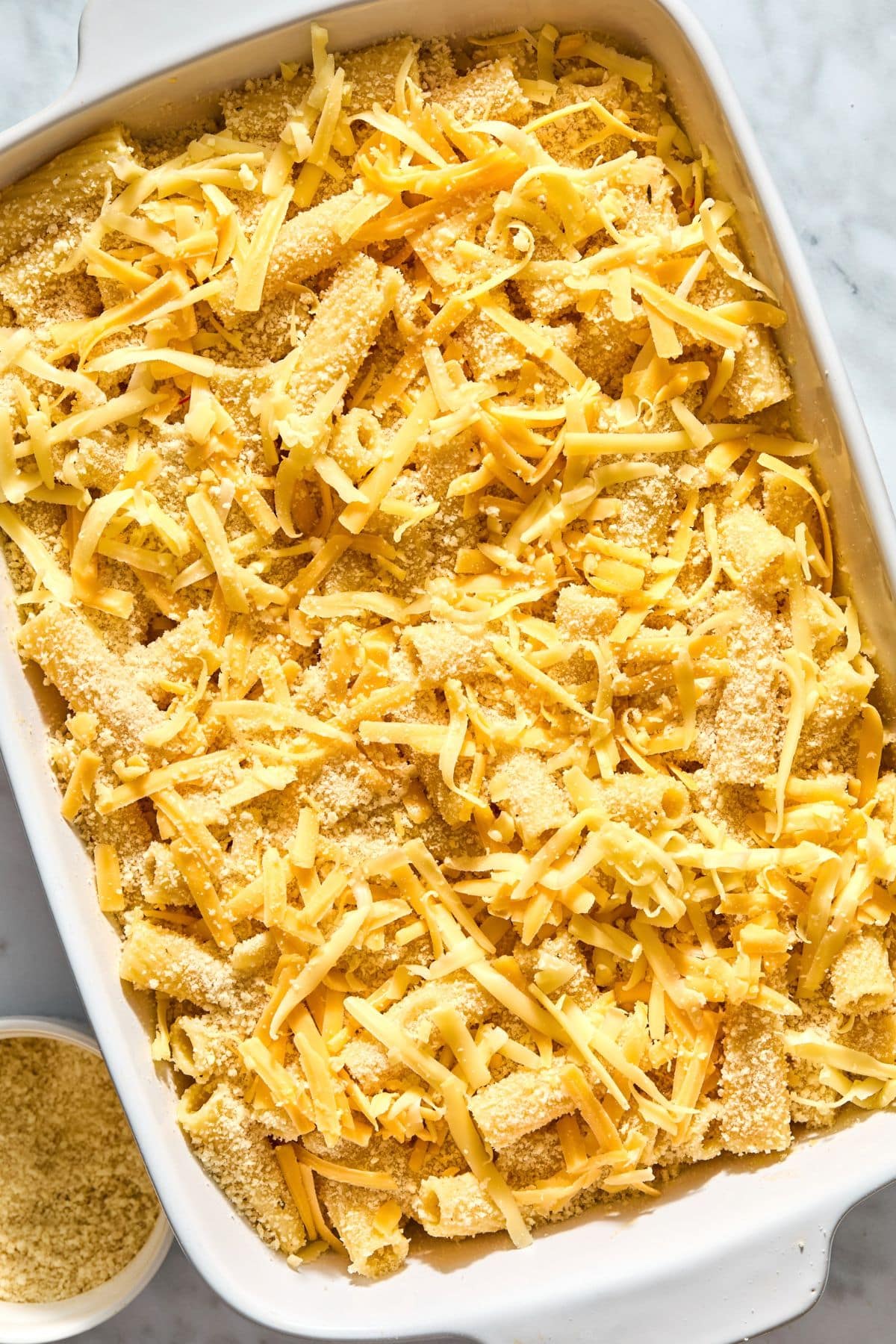 Pasta mixed into the sauce and all the ingredients added to a casserole dish.