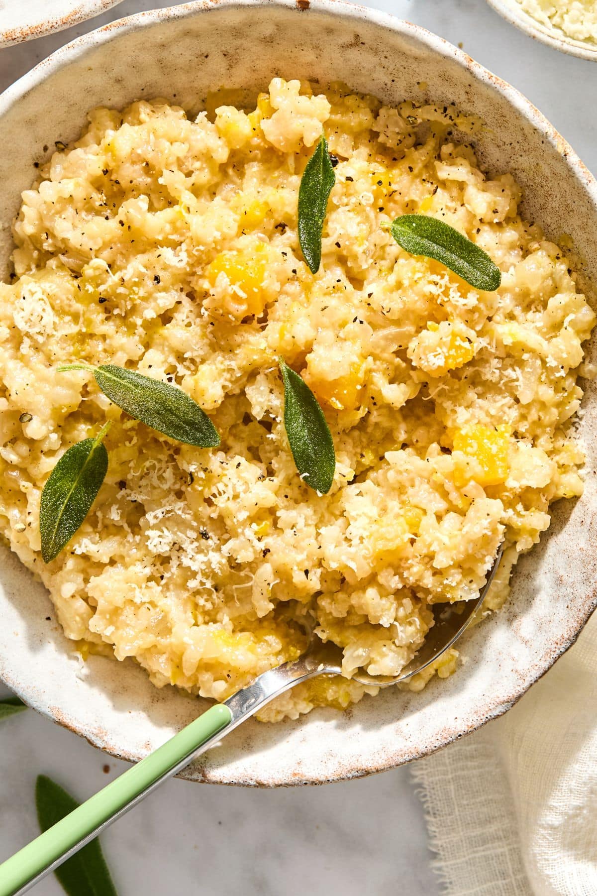 A bowl filled with risotto with butternut squash with a spoon on the side.